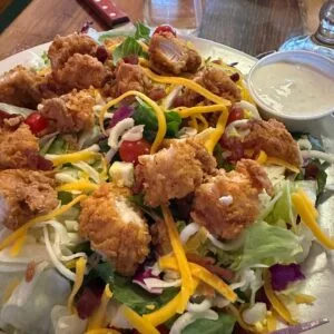 Chicken Critter Salad topped with crispy chicken and shredded cheese.