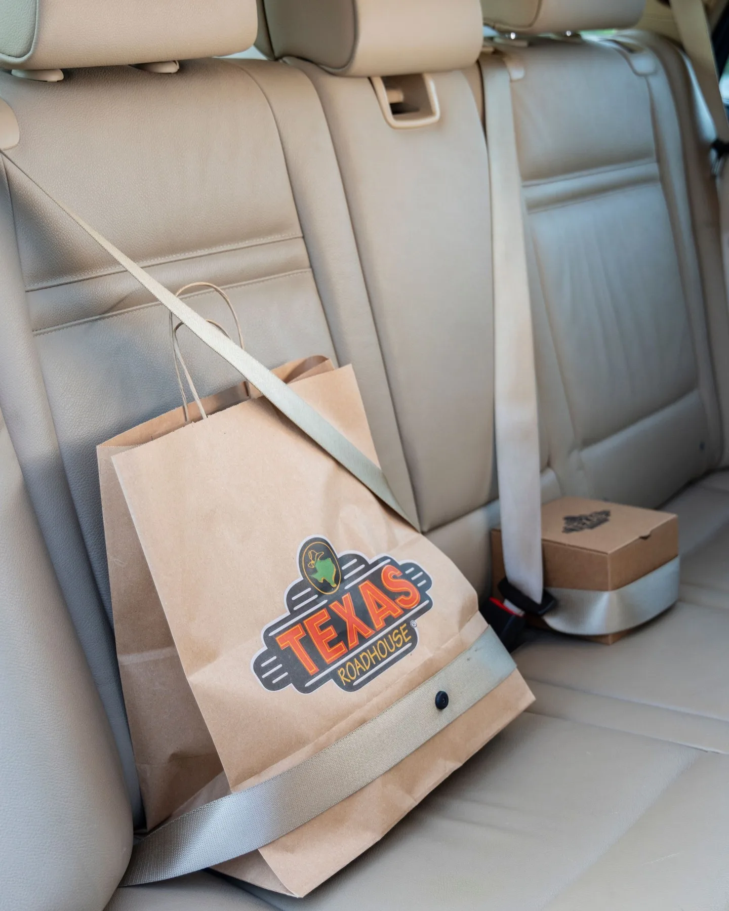 Texas Roadhouse takeout bags secured with a seatbelt