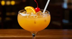 Texas Roadhouse Jamaican Cowboy cocktail with orange slice and cherry garnish on a rustic wood table.