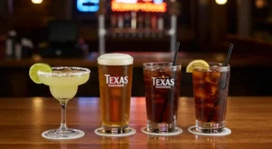 Texas Roadhouse drink menu with margaritas, beer, iced tea, and soft drinks on a wooden bar counter in a Western-themed restaurant